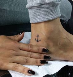 two people with black nail polishes on their feet and one has an anchor tattoo