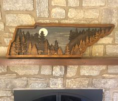 a fireplace mantle with a wood carving of a forest scene on it and a full moon in the background