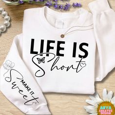 a white shirt with the words life is short on it and some flowers next to it