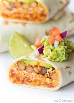 two burritos with guacamole, beans and avocado on top