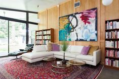 a living room filled with lots of furniture and bookshelves next to a large window