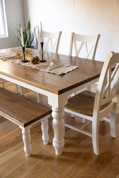 a wooden table with two white chairs next to it and a potted plant on top