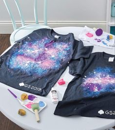 two children's shirts on a table with paint and play doughnuts next to them