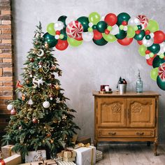 a decorated christmas tree in front of a fireplace with presents under it and balloons on the wall