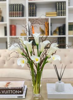 a vase filled with white flowers sitting on top of a table next to a book