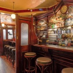 an old fashioned bar with stools and clock on the wall