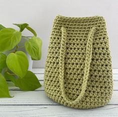 a purse sitting on top of a white table next to a green leafy plant