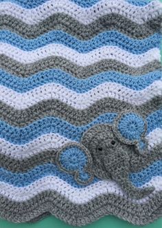 an elephant crocheted blanket on top of a blue and white table cloth with waves