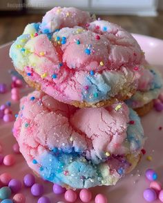 two pink and blue cookies on a plate with sprinkles