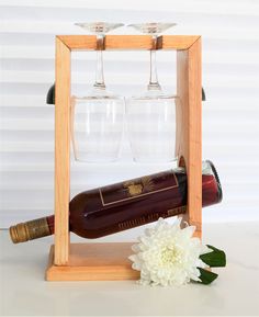 two wine glasses and a bottle in a wooden holder