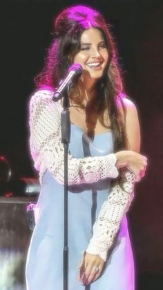 a woman standing in front of a microphone with her hands on her hips and smiling