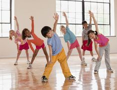 a group of young children standing on top of a wooden floor next to each other