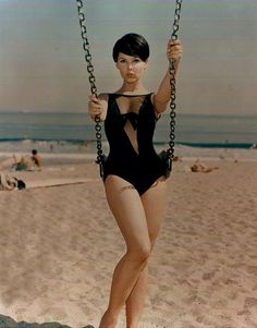 a woman in a bodysuit on a swing at the beach