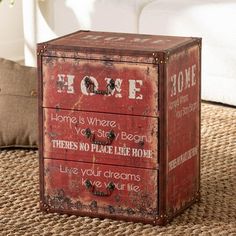 an old red metal box sitting on top of a rug next to a white couch