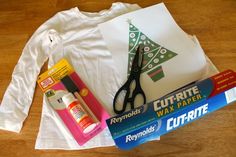 craft supplies laid out on top of a wooden floor next to a t - shirt