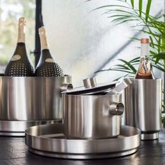 two wine bottles are sitting on the table next to pots and pans with lids