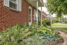 a brick house with lots of plants in front