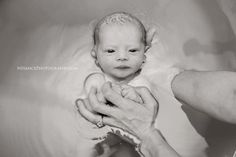 a black and white photo of a baby in a bathtub being held by an adult