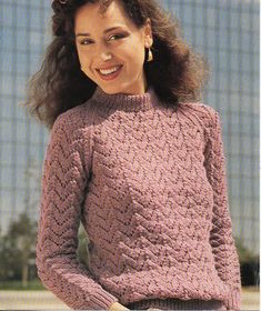 a woman in a pink sweater smiles at the camera with her hands on her hips