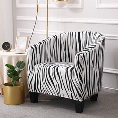 a zebra print chair next to a potted plant in a white and black living room