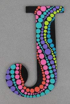 the letter j is decorated with multicolored circles and dots on black, gray background