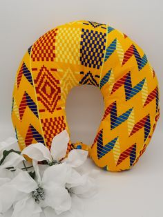 a yellow and red decorative pillow next to white flowers