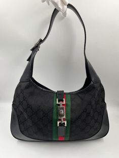 A stunning vintage Gucci Jackie bag made from black canvas with black leather trim and silver hardware. This bag also has the iconic Gucci pin lock closure. Inside the bag is lined with the black Gucci nylon lining and there is a zipped pocket for valuables. This bag is in good vintage condition, with some minor wear to the hardware and leather parts. Height: 19cm Width: 32cm Depth: 4cm Vintage Gucci Jackie, Pin Lock, Vuitton Bag, Black Canvas, Leather Trim, Silver Hardware, Gucci Jackie Bag, Vintage Gucci, Gucci Bag