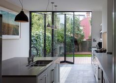 an open kitchen with sliding glass doors leading to the back yard and garden area, as well as stainless steel appliances