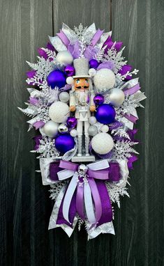 a purple and white wreath with ornaments hanging from it