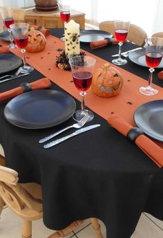 the table is set with black plates, silverware and red wine glasses on it