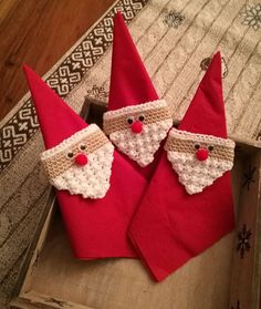 three red christmas napkins with crocheted santa claus faces on them sitting in a wooden box