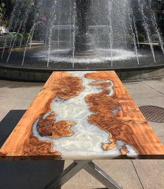 a wooden table sitting in front of a fountain with water spouting from it