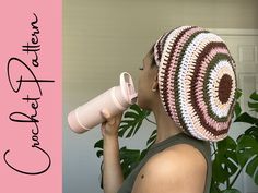 a woman with a crocheted hat is drinking from a cup and holding a coffee mug