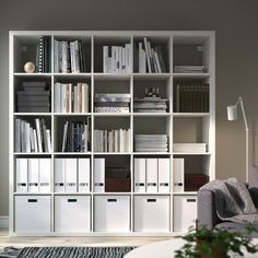 a living room filled with lots of white bookshelves next to a gray couch