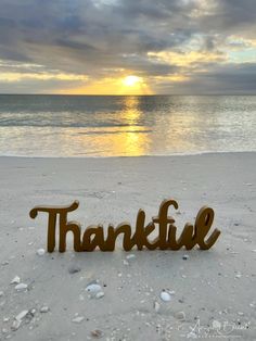 a wooden sign that reads, thank on the sand near the ocean at sunset or dawn