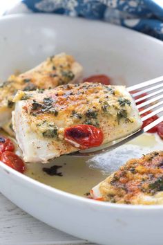 a white bowl filled with fish covered in marinara sauce and topped with a fork