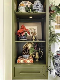 a green cabinet with christmas decorations and other items in it's display case on the wall