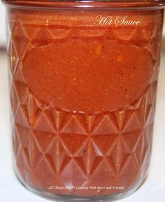 a jar filled with hot sauce sitting on top of a counter