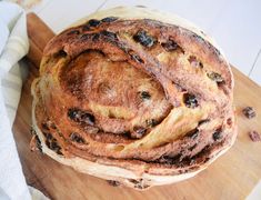 a loaf of raisin bread sitting on top of a wooden cutting board next to a white towel