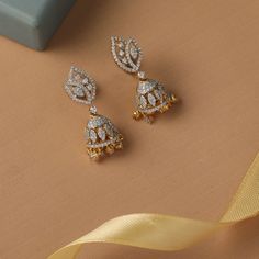 Description : Leafy CZ Jhumki Earrings reflect the sheen and shape of the mini jhumki motif suspended from a leaf stud motif studded with CZ stone. Wear these intricately handcrafted silver Jhumki on their own or with classic jewelry for exquisite styling. Details & Specification : Materials used: Brass Alloy with White Rhodium / Gold & White Gold Platting Weight - 8.10gm Length - 3cm Make it custom : Want to make it a custom Earrings? Sure! Reach out to us at support@tarinika.com and we’ll be h White Stone Earrings Jumkas, Cz Earrings Buttalu Gold, White Stone Earrings Indian Gold, White Stone Gold Jhumka, Gold Dual-tone Jhumkas For Festive Occasions, Gold Stone Work Dangle Jhumkas, Buy Jewellery Online, Jhumki Earrings, Indian Jewellery Design