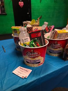 several buckets of food sitting on top of a blue cloth covered table with a price tag