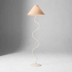 a floor lamp with a white base and a beige shade on the top of it