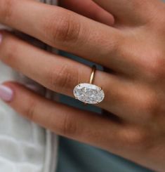 a woman's hand holding a ring with a diamond in the middle and a gold band around it