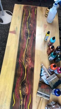 a wooden table topped with lots of paint and supplies