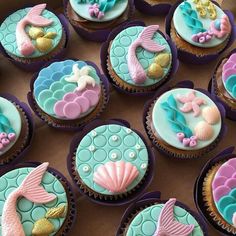 cupcakes decorated with fondant sea animals and seashells are on display