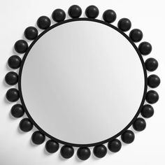 a round mirror with black balls around it