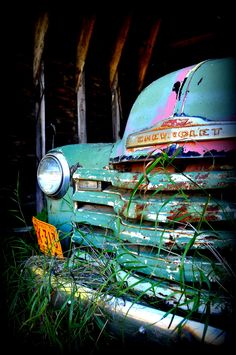 an old truck is sitting in the grass