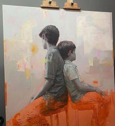 two boys sitting on top of an orange painting with their arms around each other's shoulders