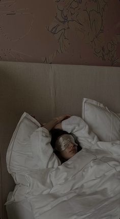 a woman laying in bed with her head under the covers