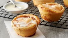 some kind of pastry sitting on top of a cooling rack next to a bowl of cream